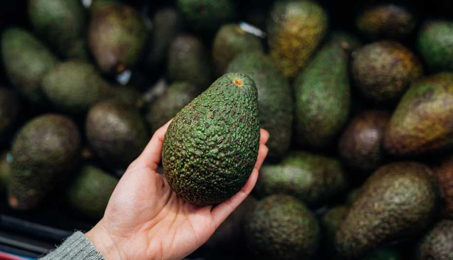 woman holding fresh avocado