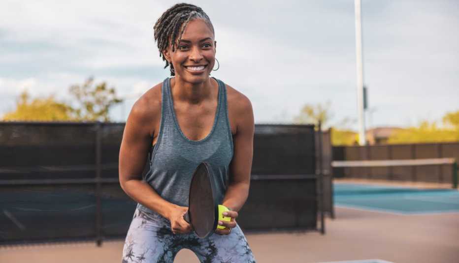 a smiling woman is preparing to serve in a game of pickleball