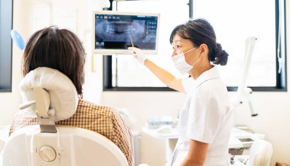 dentist pointing to a dental xray with a patient sitting in the chair