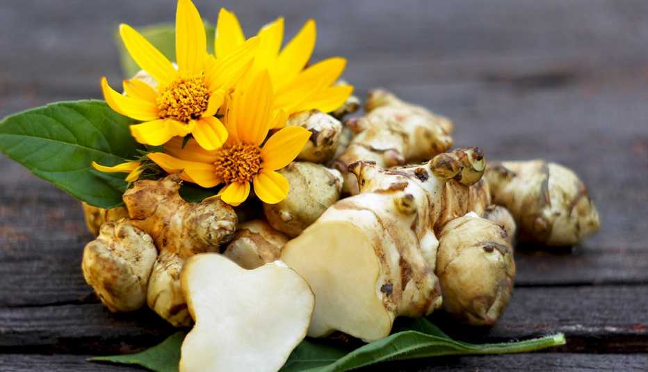 Jerusalem artichoke and its yellow flowers on wooden table background