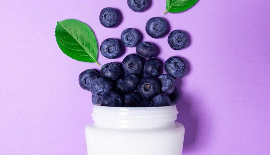 Creative beauty fashion concept photo of cosmetic recyclable bottle lotion cream with blueberry on purple background.