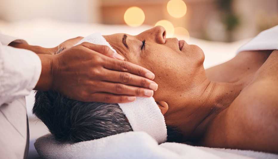 woman lying with eyes closed on massage table getting a temple massage