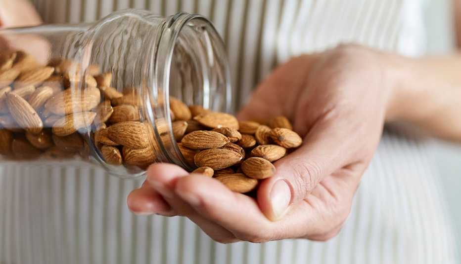 woman taking almonds from a glass jar