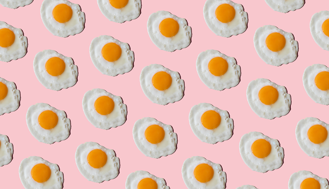 Dozens of fried, sunny-side up eggs on a light pink background
