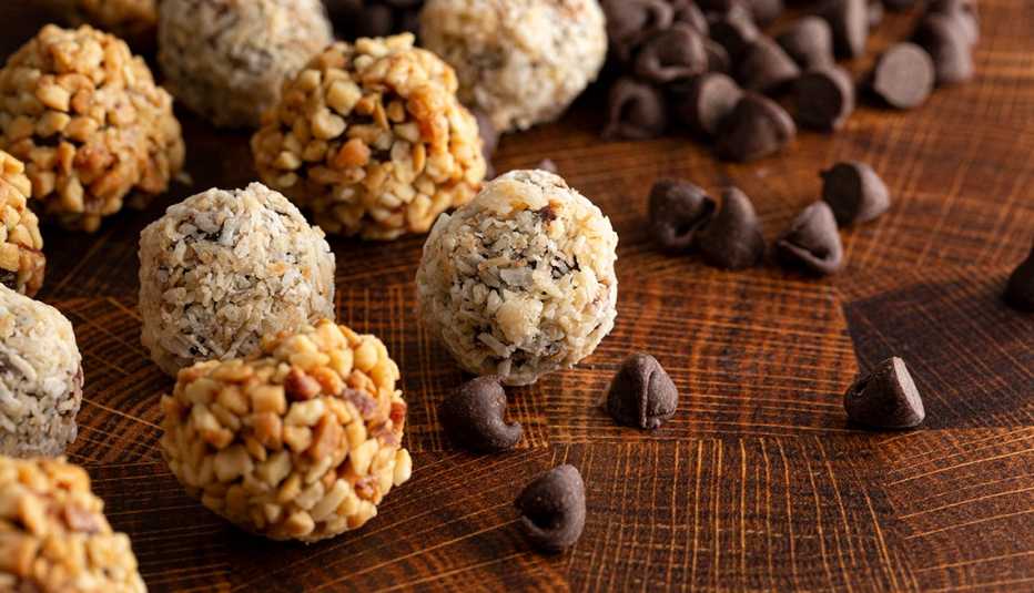 close up of healthy peanut butter balls with coconut shavings and chocolate chips on a wooden butcher block