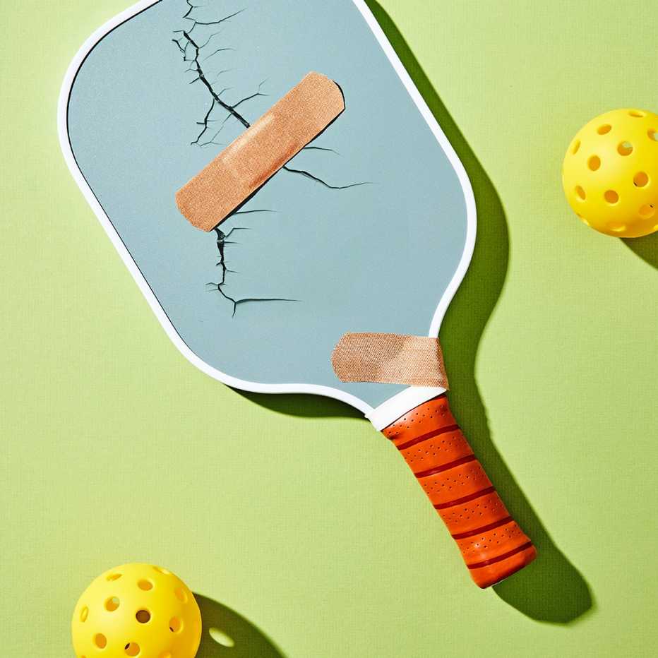 pickleball paddle with a crack on it covered by a band aid