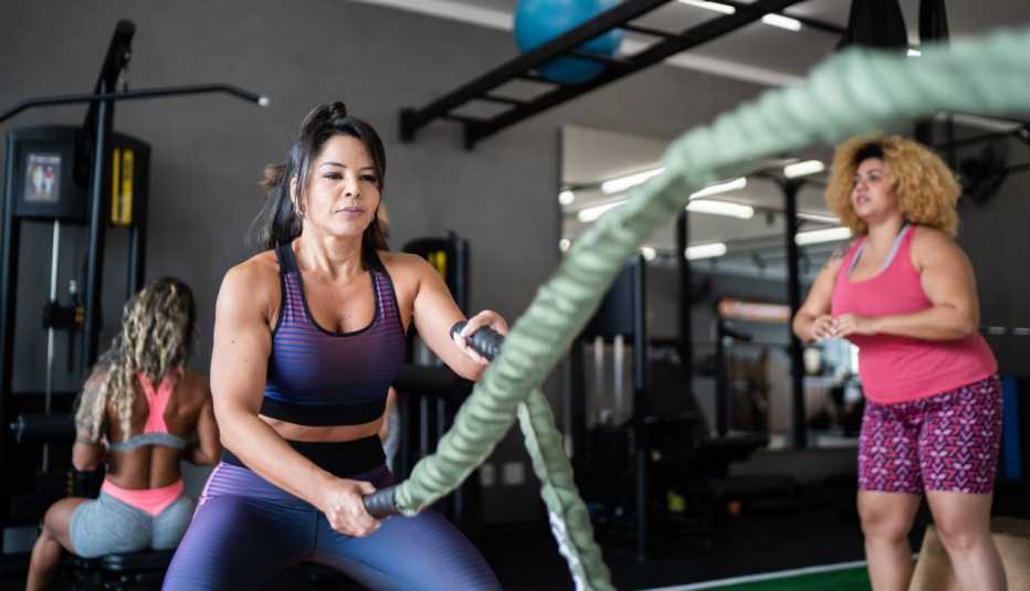  a woman works out with battle ropes at the gym