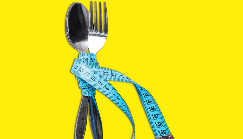 close up of a fork and spoon wrapped together with a blue tape measure to represent how eating less slows aging