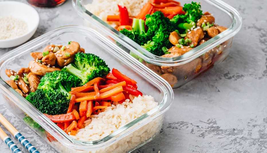 two meals of teriyaki chicken broccoli red pepers and rice that are portioned into containers 