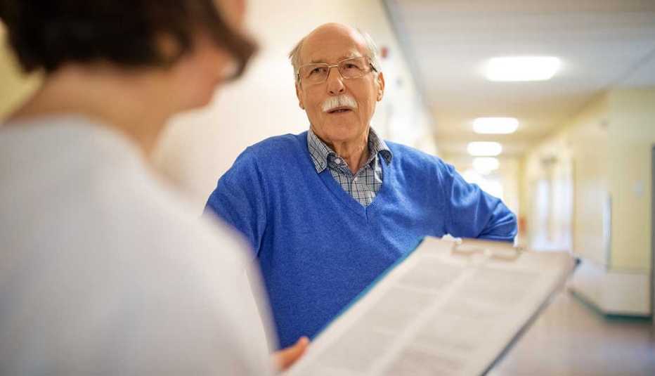 Senior man talking with doctor in hospital hallway. 