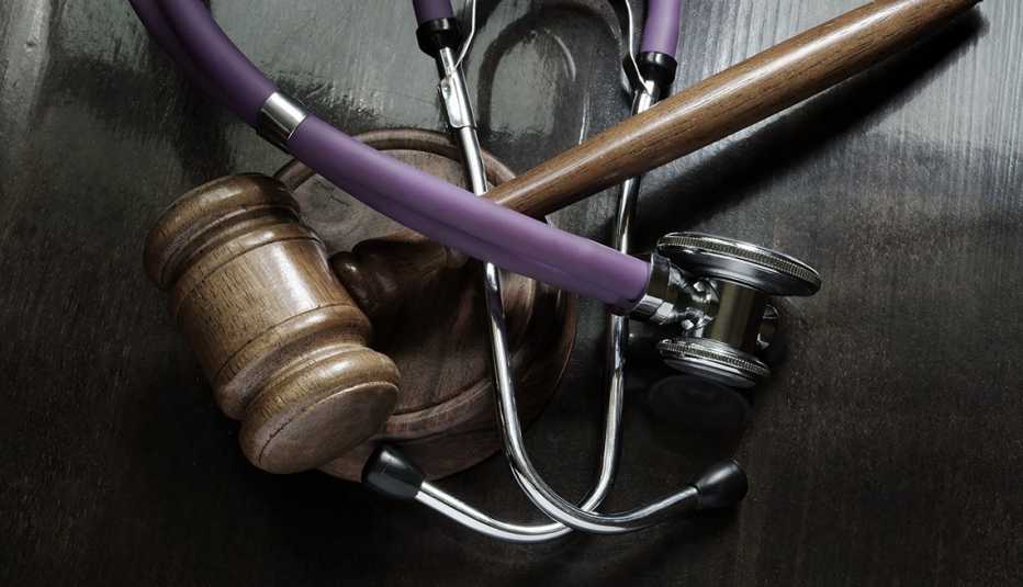 A brown gavel is wrapped with a stethoscope on a table