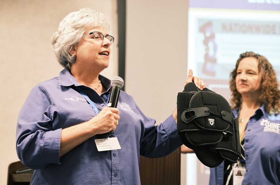 volunteer medicare counselor betsy dubin giving a talk and holding a back brace