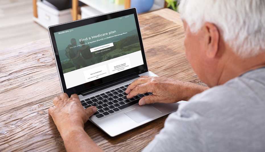 A man sitting in front of a laptop looking at the redesigned Medicare Plan Finder website