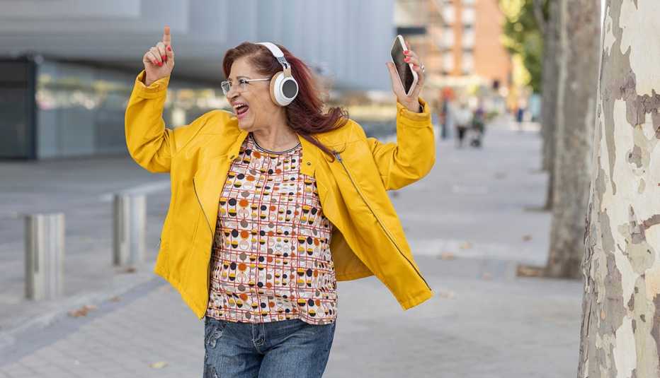 woman singing and dancing to music on her headphones on the street