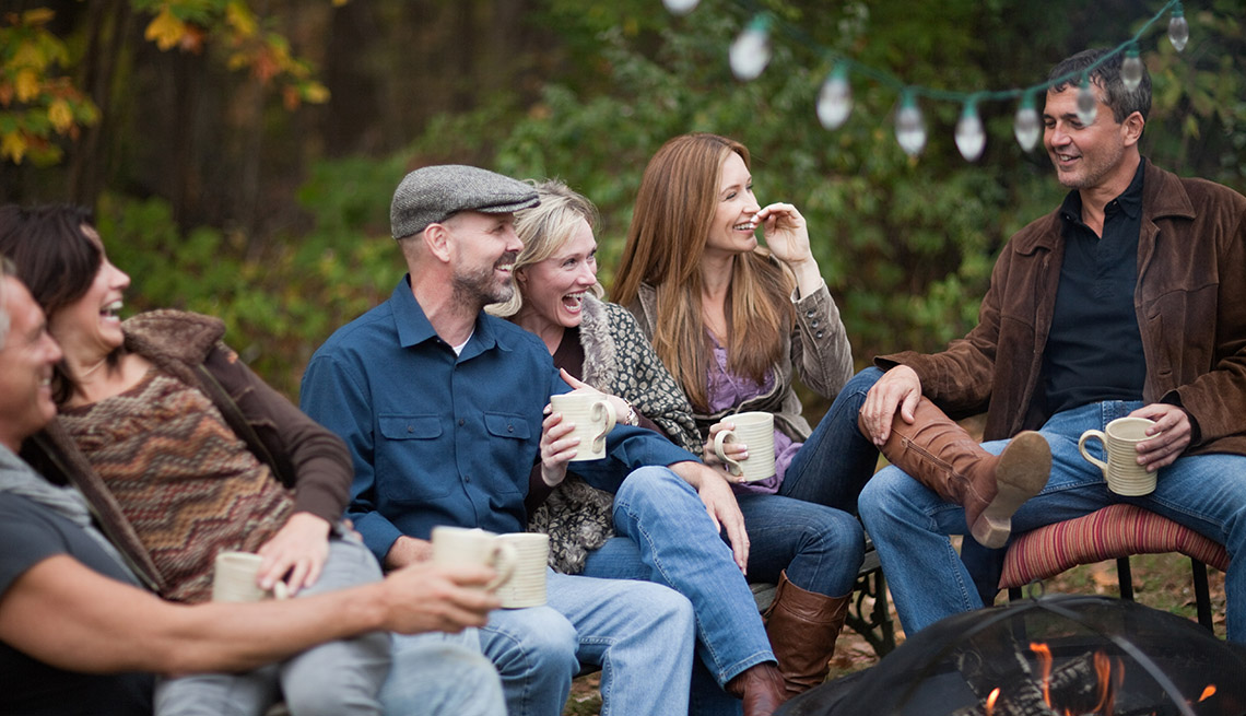 A Group Of Friends Hang Out And Laugh Together Outdoors By Firepit, AARP Home And Family, 5 Ways To Be Closer To Your Friends