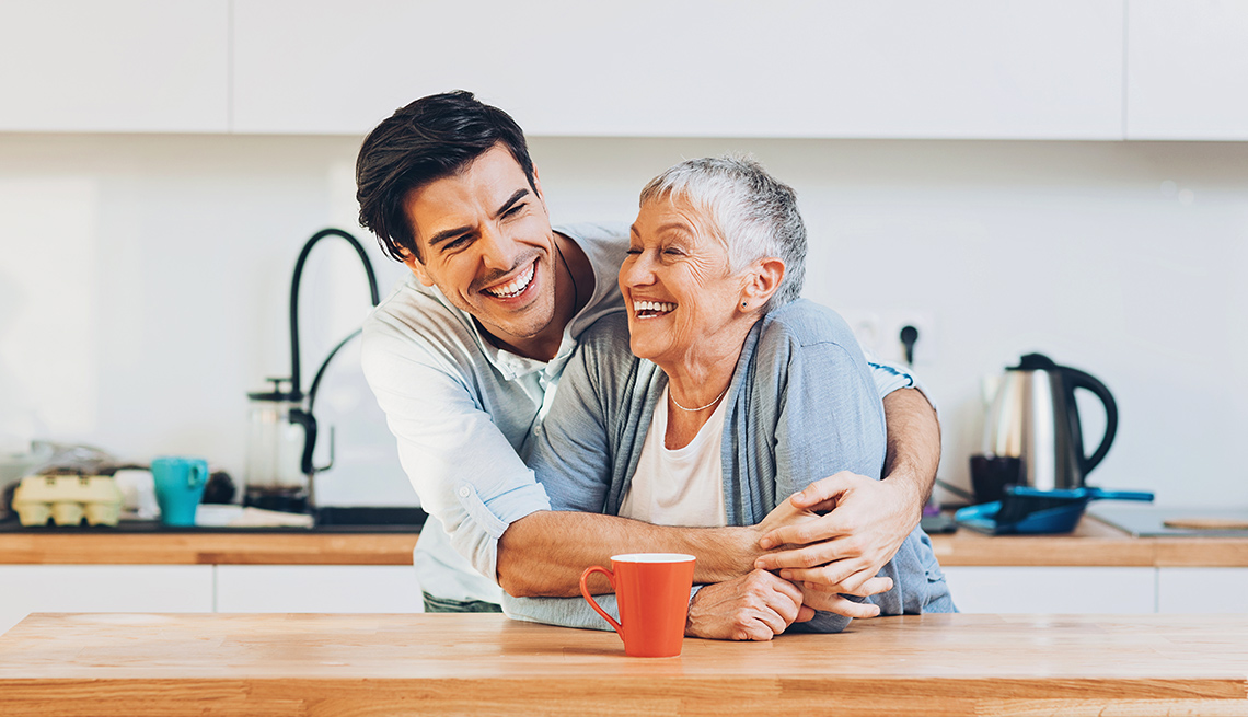 A son and senior mother laughing in kitchen