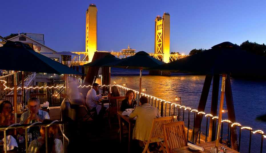 Open air restaurant along the Sacramento River in the evening with a view of the tower bridge in the background