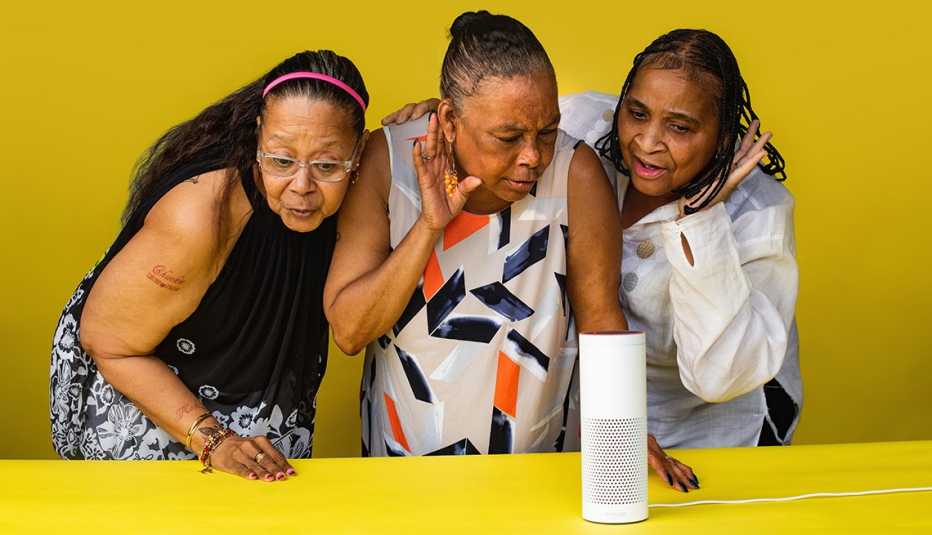 Three women listening to a smart speaker.