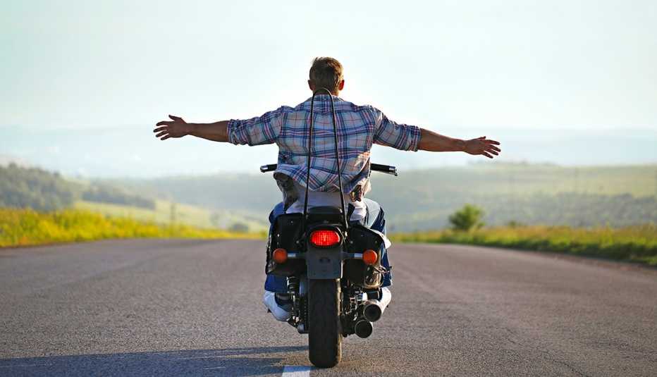 Man riding motorcycle with arms outstretched