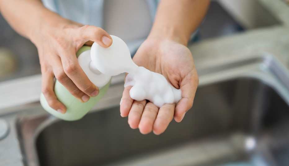 Woman washing or sanitizing her hands at the kitchen sink