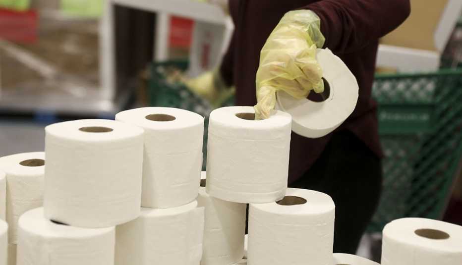 A volunteer picks up rolls of toilet paper at a Midwest Food Bank distribution warehouse in Normal, Illinois, U.S., on Wednesday, May 13, 2020. The coronavirus pandemic is forcing food banks across the country to find new ways to feed people  from slaught