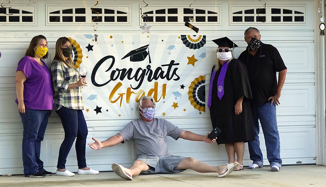 Linda White, third from right, poses with family and friends as she wears her cap and gown while celebrating graduating with a bachelor of science in elementary education and special education from Grand Canyon University during the coronavirus outbreak, 