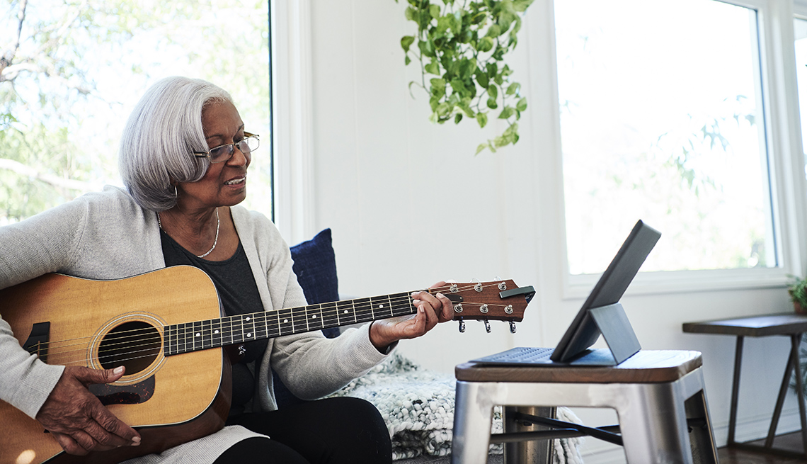 Woman learning to play a guitar on her tablet device