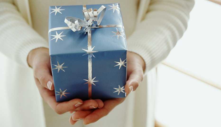 A closeup of a woman holding a blue wrapped gift box