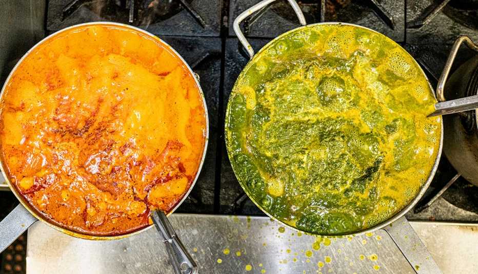 two indian food sauces simmer on a restaurant stove as seem from above