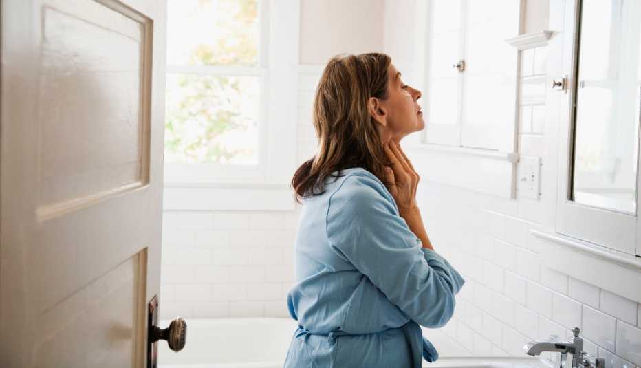 woman checking her skin in the bathroom mirror