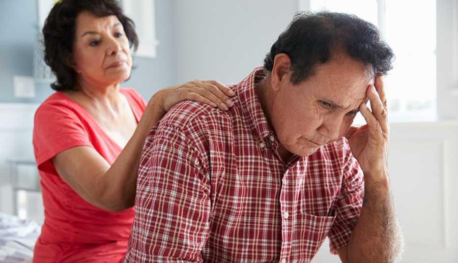 Woman with her hand on her husband's shoulder, comforting him as he grieves