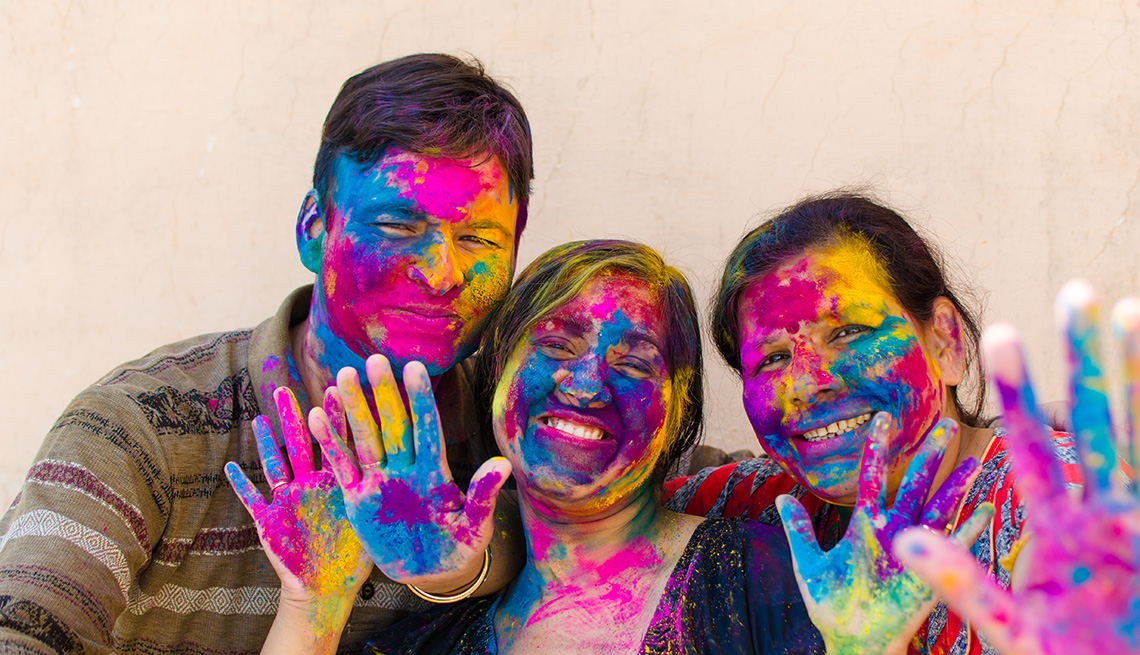 Indian family (mother son and daughter) with colorful face, smiling and looking to camera in festival Holi