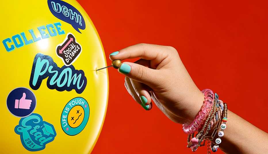 a young girls hand sticks a pin into a balloon with stickers on it that says things like college and prom and ugh