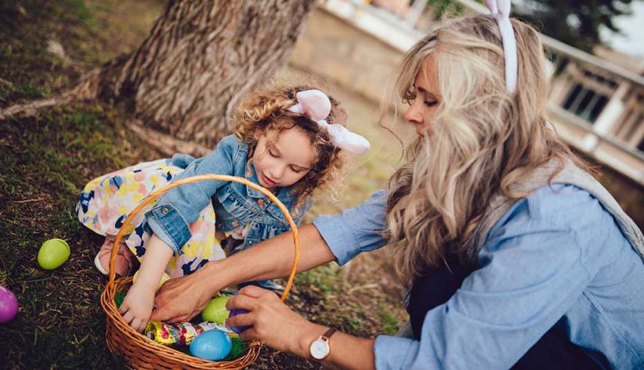 Grandmother and little granddaughter having fun in garden collecting eggs during Easter Egg hunt
