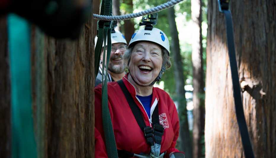 A woman on a zip line in the woods laughing