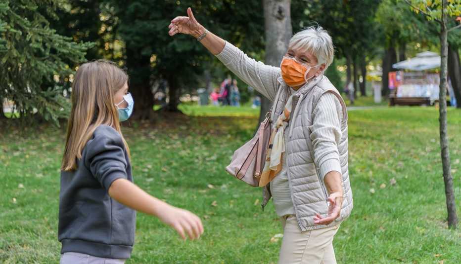 granddaughter and grandmother greet each other wearing masks and holding out arms for a hug