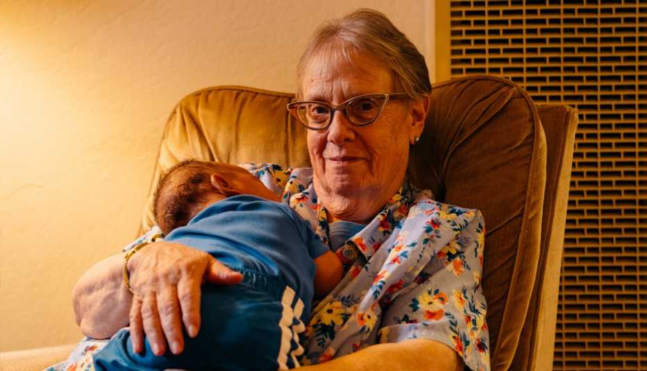 foster mother linda owens sits in a chair cuddling a baby