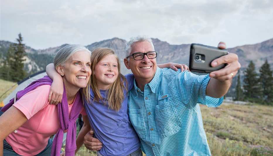  grandparents and granddaughter posing for cell phone selfie at a park