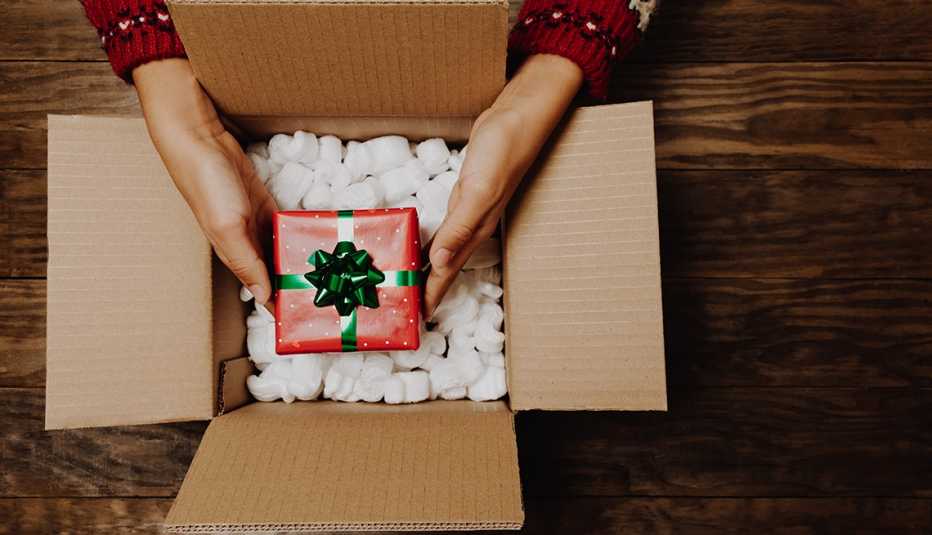a woman packing a Christmas gift in a shipping box