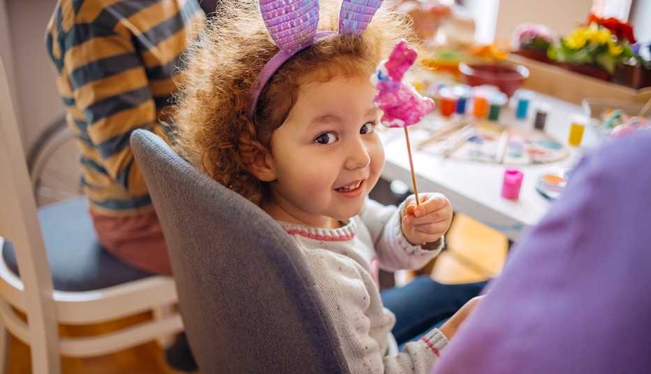 toddler showing a painted Easter bunny while sitting at table during family craft activity for Easter