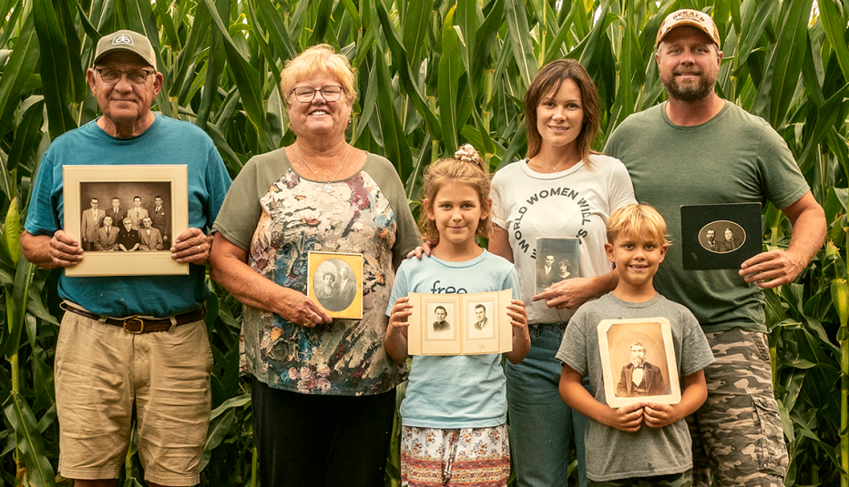the vetter family standing in front of their corn field holding portraits of their ancestors