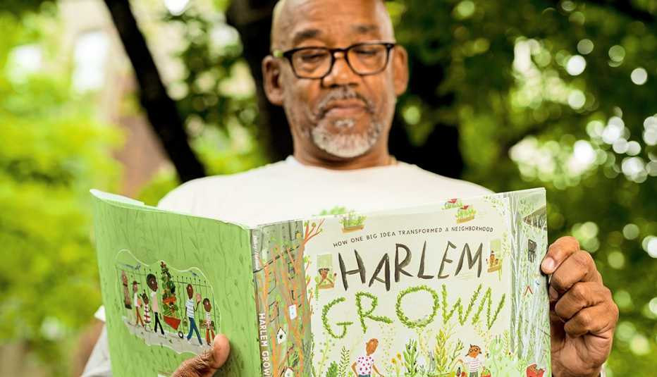 Tony Hillery, founder and executive director of Harlem Grown, poses for a portrait with his book "Harlem Grown" at the 134th street Harlem Grown garden.