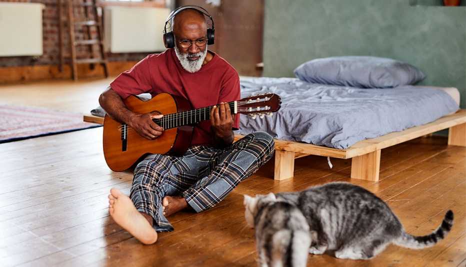 a man learning guitar playing for his curious cats
