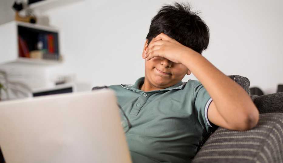 teenage boy with laptop covering his face