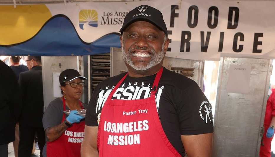 pastor troy vaughan in a red apron that says los angeles mission