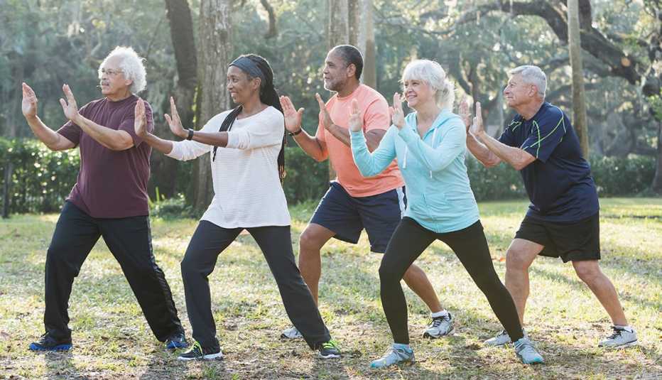 diverse group of five seniors practicing tai chi outdoors