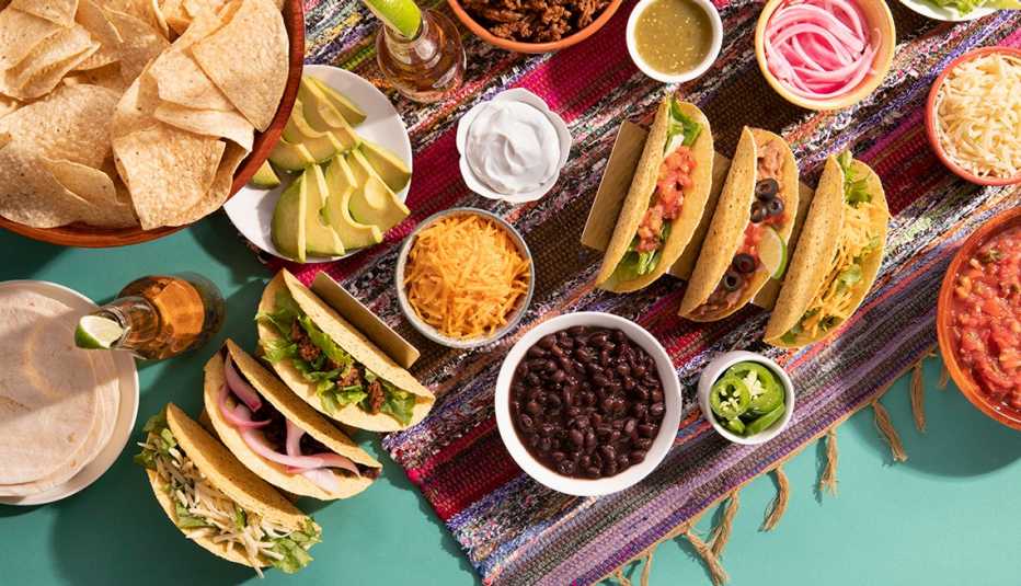 an assortment of tacos and toppings on a table