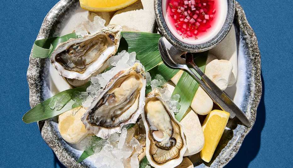 a plate of oysters on ice with lemon