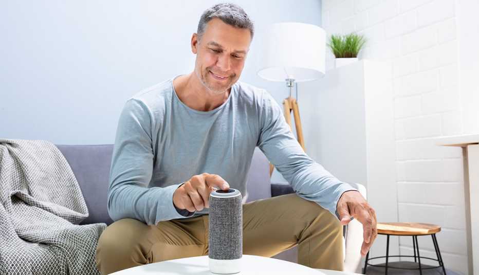 Man Pressing Button On Wireless Speaker At Home