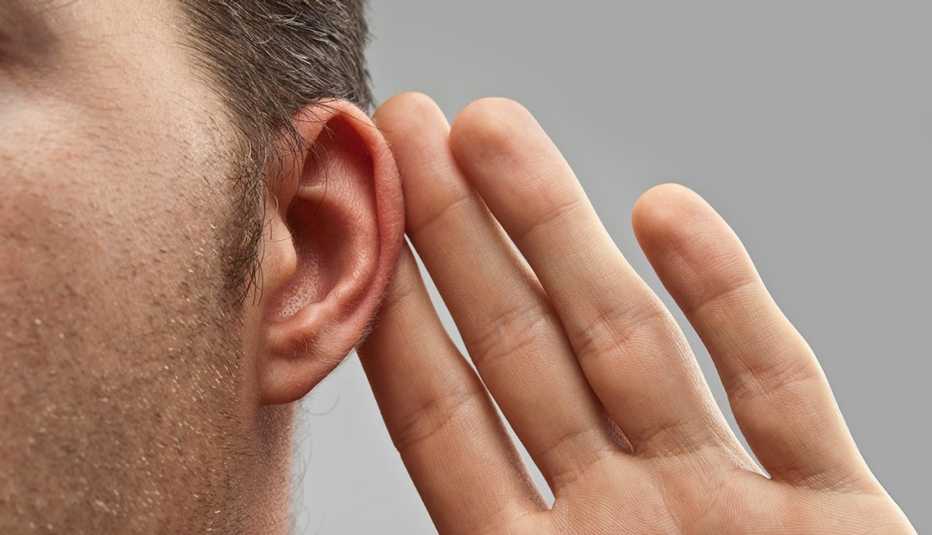 close up view of a man holding his fingers up to his ear in the universal gesture of listening